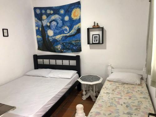 SURFuncional Guest House في بيرتيوغا: غرفة نوم بسريرين ولوحة على الحائط