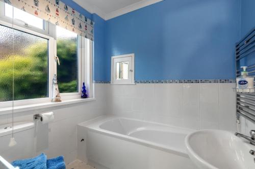 a bathroom with a tub and a sink and a window at Four Oaks - Sea and Harbour Views in Saundersfoot