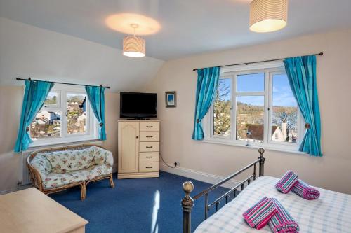 a bedroom with two beds and a chair and a television at Four Oaks - Sea and Harbour Views in Saundersfoot