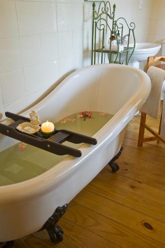 a white bath tub with a candle in a room at Centre-Ville Guest House in Franschhoek
