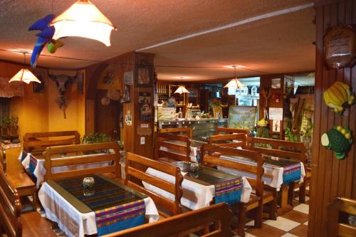 un restaurant avec des tables et des chaises en bois ainsi qu'un bar dans l'établissement La Quiteñita Papallacta, à Papallacta