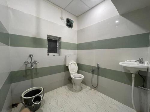 uma casa de banho com um WC e um lavatório em Assam Villa - by Storyweavers Retreat em Jorhāt