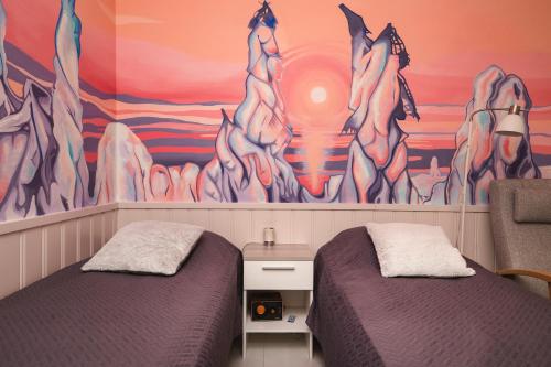 two beds in a room with a mural on the wall at Cozy studio with sauna in the middle of Levi in Kittilä