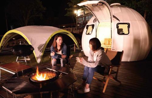 Due donne sedute davanti a una tenda di Kuruma Asobi Adventure Field Appi - Camp - Vacation STAY 42063v a Hachimantai