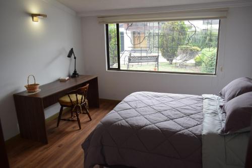 a bedroom with a bed and a desk and a window at Casa Pabón in Bogotá