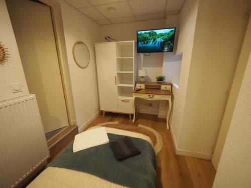 um pequeno quarto com uma secretária e uma televisão na parede em Appartement meublé 4 - 15 min Dampierre - 25 min Belleville - WIFI em Gien