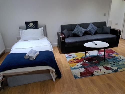 a bedroom with a bed and a couch and a rug at Simply Relax, Eastham London in London