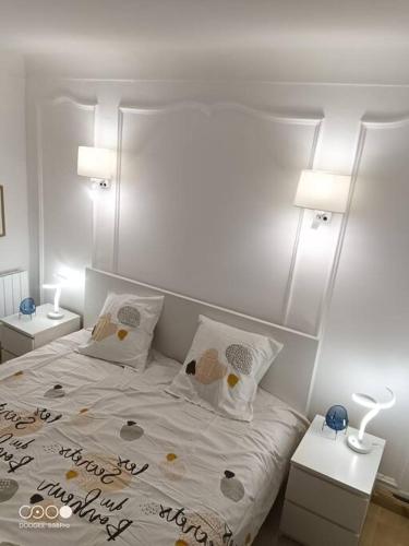 - une chambre dotée d'un lit blanc avec deux tables et deux lampes dans l'établissement Aramis Colibri 72m2, lit king-size, baignoire duo hôte non professionnel, à Paris