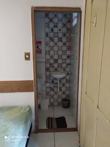 a bathroom with a toilet with a tile wall at Flora Pousada in Recife