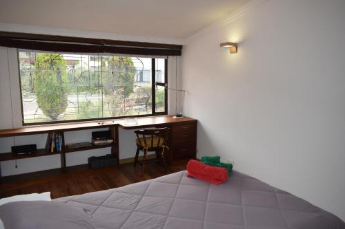 a bedroom with a bed and a desk and a window at Casa Pabón in Bogotá