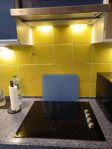 - une cuisine équipée de plaques de cuisson et d'une chaise bleue dans l'établissement Aramis Colibri 72m2, lit king-size, baignoire duo hôte non professionnel, à Paris