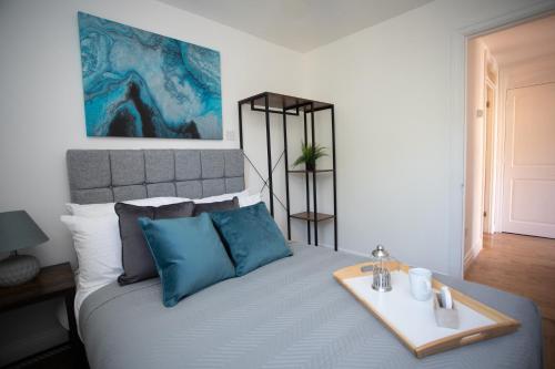 a bed with blue pillows and a tray on it at Apartment in the heart of Old Town Beaconsfield in Buckinghamshire