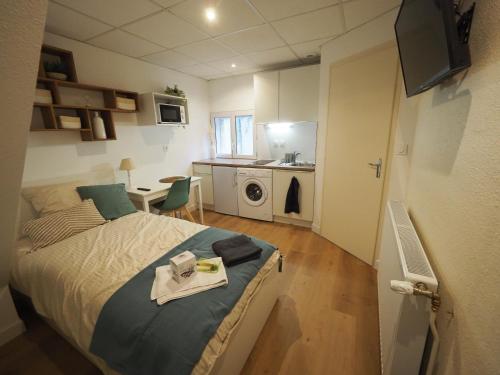1 dormitorio con cama, mesa y cocina en 8 appartements - studio - F2 - WIFI gratuit, en Gien