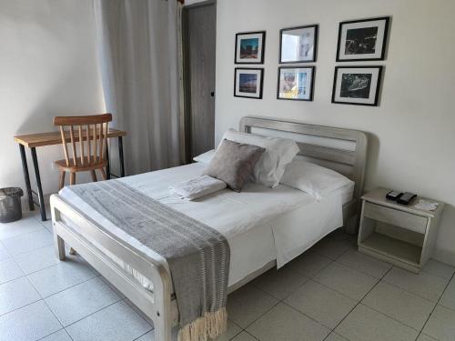 1 dormitorio con 1 cama con silla y cuadros en la pared en Hotel Casa de las Dos Palmas -Hotel Boutique, en Puerto Berrío