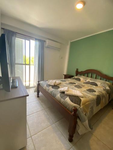 a bedroom with a bed and a tv and a window at Departamento Good Vibes 2 in Paraná