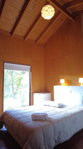 a bedroom with a large bed with a window at Bungalow Sobre Águas Camping in Bragança