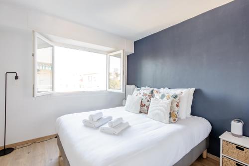 une chambre avec un lit blanc avec un mur bleu dans l'établissement Bright 2 Bed Apt in Cannes, 10 min to Palais, à Cannes