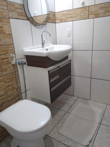 La salle de bains est pourvue de toilettes, d'un lavabo et d'un miroir. dans l'établissement Pousada Recanto Guatambu - Sobrado, à Chapada dos Guimarães