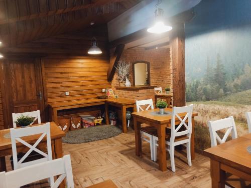 Beskidówka z sauną w cenie pobytu في أوسترون: غرفة طعام مع طاولات خشبية وكراسي بيضاء