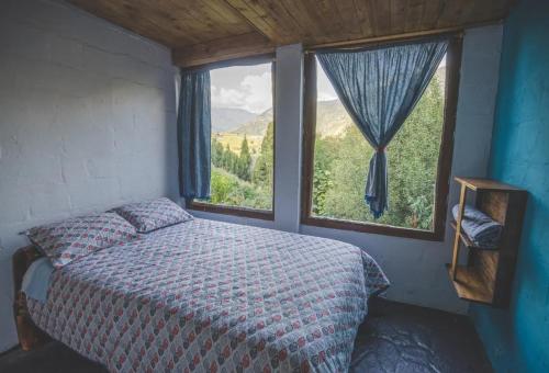 a bedroom with a bed and a large window at URKU ALLIPACHA Mountain Retreat w/ Organic Garden in Baños