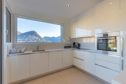 a kitchen with white cabinets and a large window at IMPERIAL of LUGANO 3 with a lake view behind the station and 10 min from the lake of Lugano in Lugano