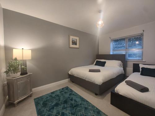 niewielka sypialnia z 2 łóżkami i dywanem w obiekcie Modern 2-Bed Gem! Prime M22 Location Near Airport, Hospital & Sleeps 7 w mieście Wythenshawe