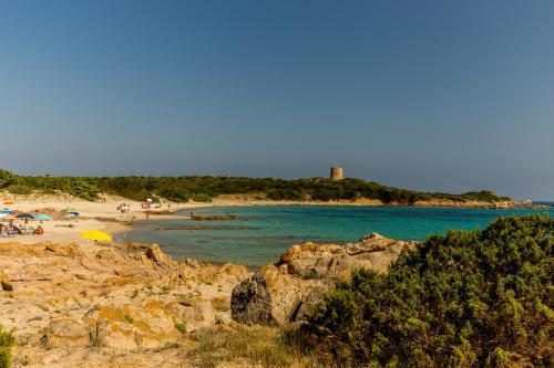 a group of people on a beach near the water at Hotel Petri Marini in Aglientu