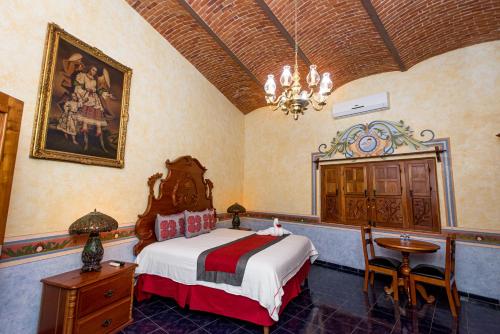 1 dormitorio con cama, mesa y lámpara de araña en HOTEL & SPA HACIENDA TRES VIDAS, en Tequisquiapan