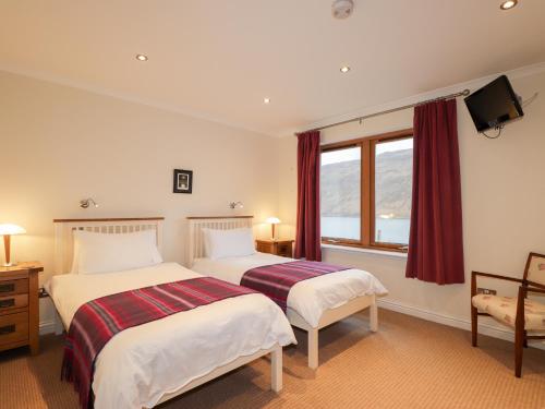 two beds in a hotel room with a window at Tigh na Creag in Sconser