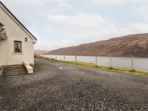 a building on the side of a road next to a body of water at Tigh na Creag in Sconser