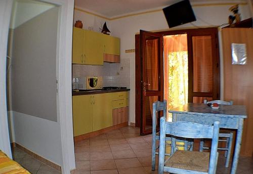 マリーナ・ディ・カンポにあるAppartamento Sciroccoのキッチン(黄色のキャビネット、テーブル、椅子付)