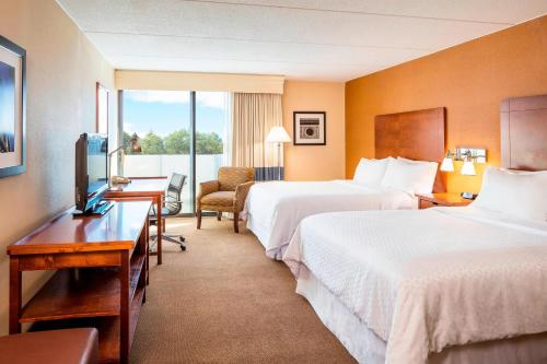 a hotel room with two beds and a television at Four Points by Sheraton Chicago O'Hare in Schiller Park