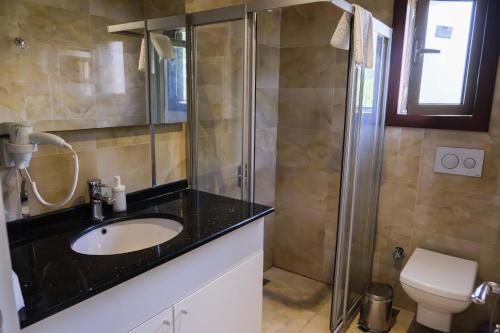 y baño con lavabo y ducha. en Apella Hotel, en Cıralı