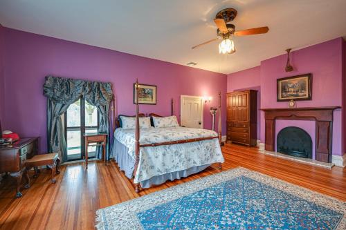 1 dormitorio con paredes moradas, 1 cama y chimenea en Historic Chambersburg Home with Pool and Game Rooms!, en Chambersburg