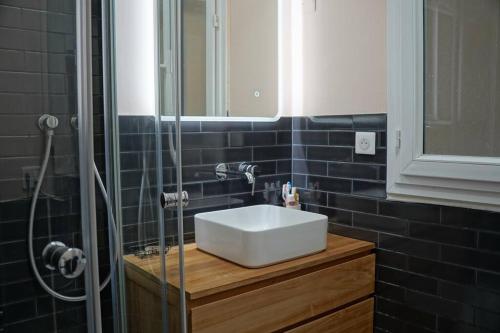 une salle de bain avec un lavabo blanc et une douche dans l'établissement Family flat, 15' away from Paris city center, à Asnières-sur-Seine