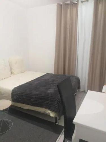 une chambre avec un lit, une table et un bureau dans l'établissement 3 chambres à louer dans l'appartement deux pas à Tramway2, à Colombes