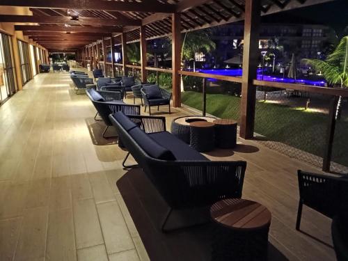 a row of chairs and tables on a patio at night at Vizinho à igrejinha - Apartamento completo no ECO RESORT Praia dos Carneiros in Praia dos Carneiros