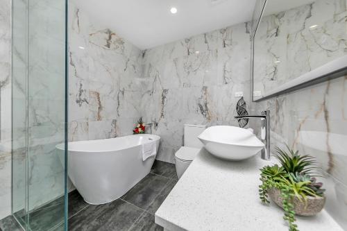 a bathroom with a tub and a toilet and a sink at Royale Palace - Rooftop Pool &Spa in Auckland