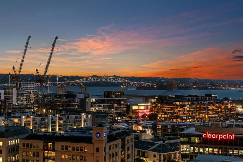 a city skyline at dusk with a bridge in the background at Royale Palace - Rooftop Pool &Spa in Auckland