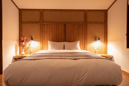 a bedroom with a large white bed with two lamps at AMAO VILLA 熱海 in Atami