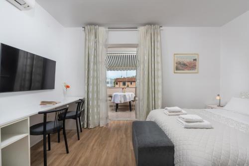a hotel room with a bed and a desk and a television at Apartments Viktor in Poreč