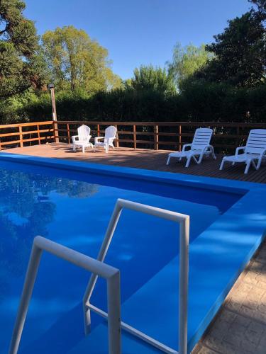 a swimming pool with white chairs and blue water at Casa Quinta Don Chilo in San Pedro