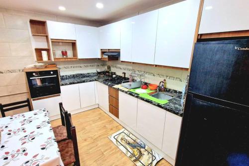 uma cozinha com armários brancos e um frigorífico preto em F2 Haut-standing millenium em Bir el Djir