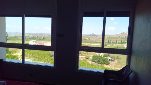 a room with three windows with views of a field at Gîte Forest Tagroumte in Azrou