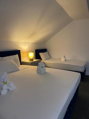 2 weiße Betten in einem Zimmer mit einer Lampe in der Unterkunft Abbie Lodge Guest House in Weston-super-Mare