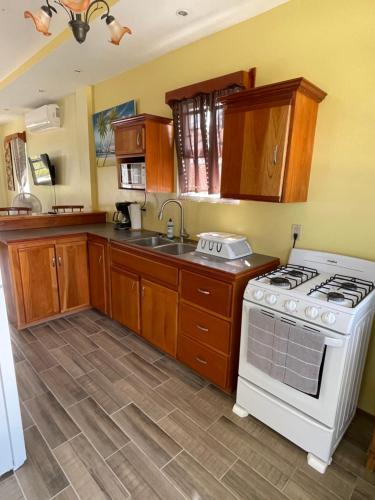 a kitchen with wooden cabinets and a white stove top oven at Hidden Treasure Vacation Home BayBlue Suite 1 in Belize City