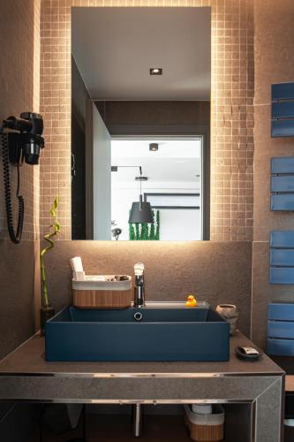 a bathroom with a blue sink in front of a mirror at SIGMA Suites Hotel in Thessaloniki