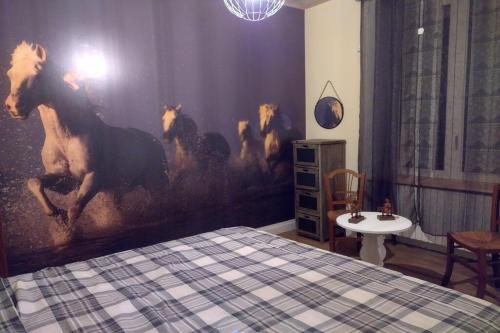 una camera da letto con un dipinto di cavalli sul muro di Le gite des galopins a Saint-Just