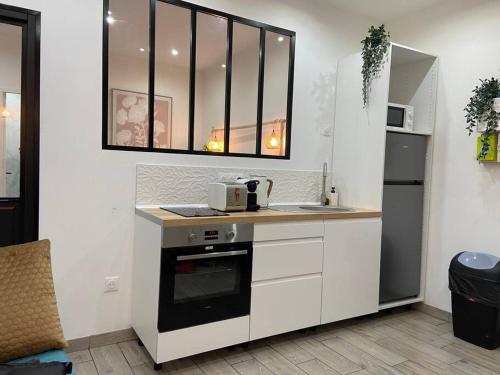 une cuisine avec des armoires blanches, un évier et un micro-ondes dans l'établissement L’Impérial au RDC, à Douai