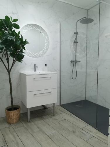 une salle de bain blanche avec un lavabo et une douche dans l'établissement L’Impérial au RDC, à Douai